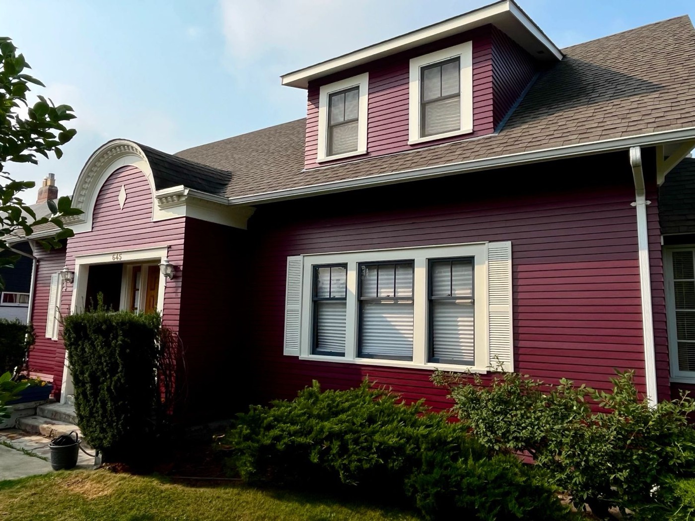 Character home with deep burgundy siding and light grey dormer