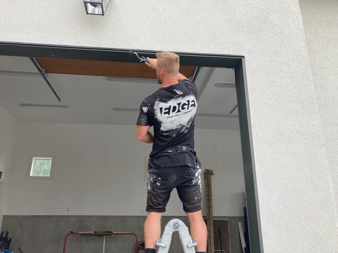 Painters rolling out a garage interior from ladders